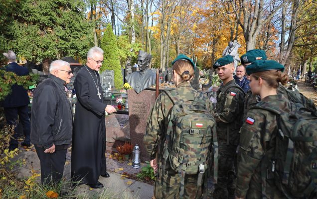 Żołnierze salutują zmarłym żołnierzom nad ich grobami, razem z nimi ksiądz.