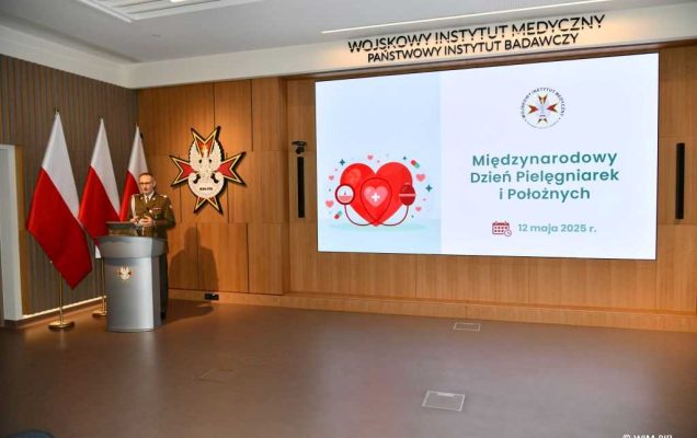 Dyrektor WIM-PIB przy mównicy. Za jego plecami wyświetlony slajd Międzynarodowy Dzień Pielęgniarek i Położnych.