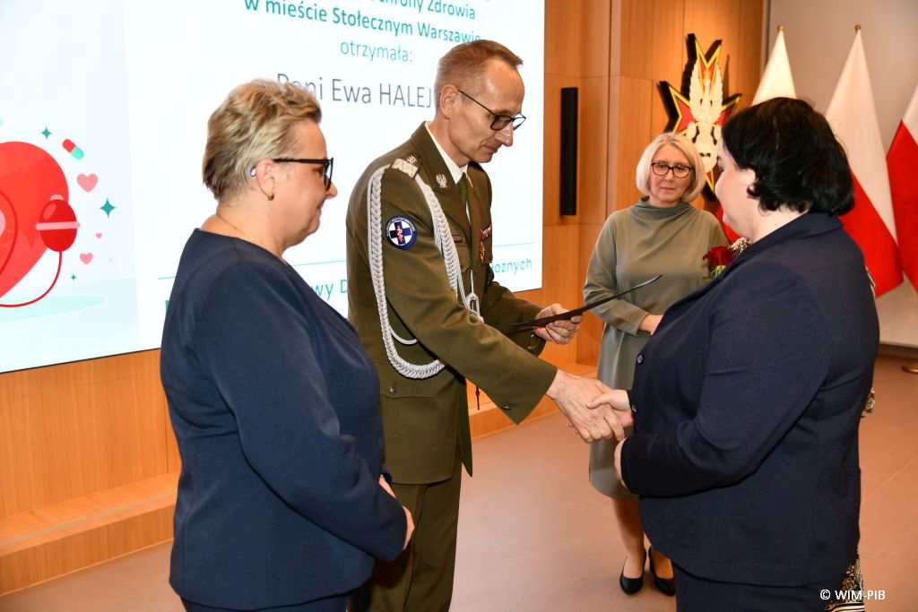 Dyrektor WIM Grzegorz Gielerak i Lidia Wojda wręczają odznaczenia i dyplomy.