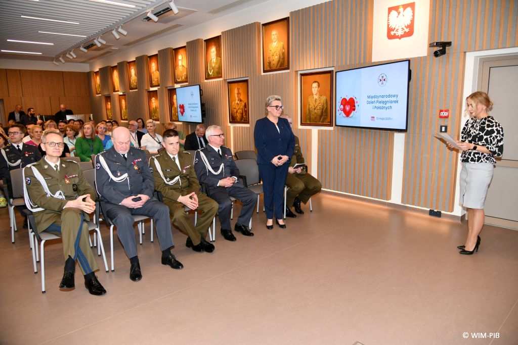 Małgorzata Złotkowska prowadzi uroczystość w Wojskowym Instytucie Medycznym. W tle uczestnicy uroczystości.