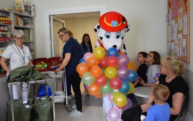 Maskotka Marshalla z Psiego patrolu z balonami wchodzi do sali pacjentów.