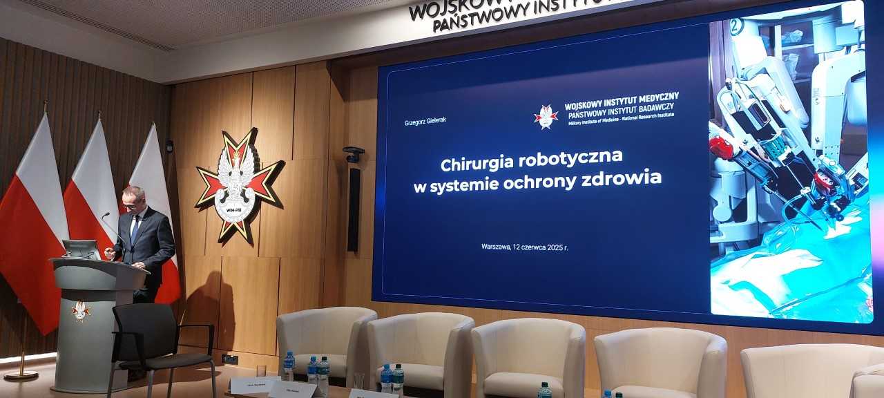 Dyrektor WIM-PIB przy mównicy. Za jego plecami wyświetlany fragment prezentacji.