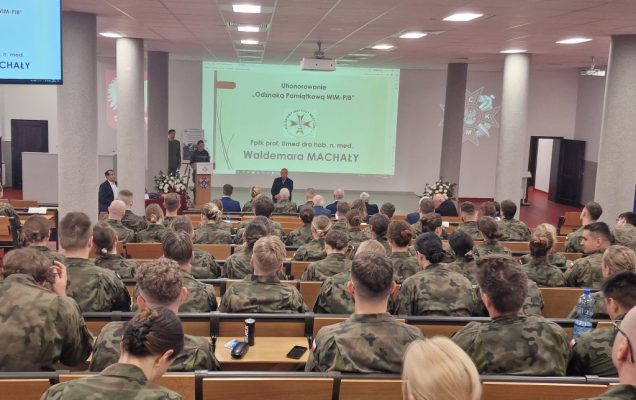 Lekarze w wojskowych mundurach siedzą na auli podczas konferencji.