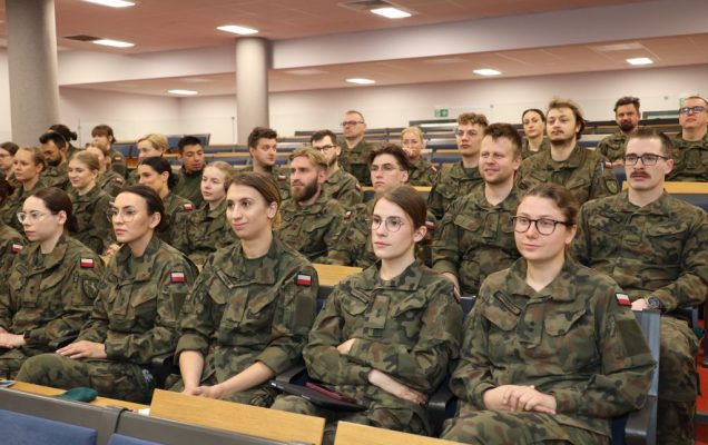 Lekarze w wojskowych mundurach siedzą na auli podczas konferencji.