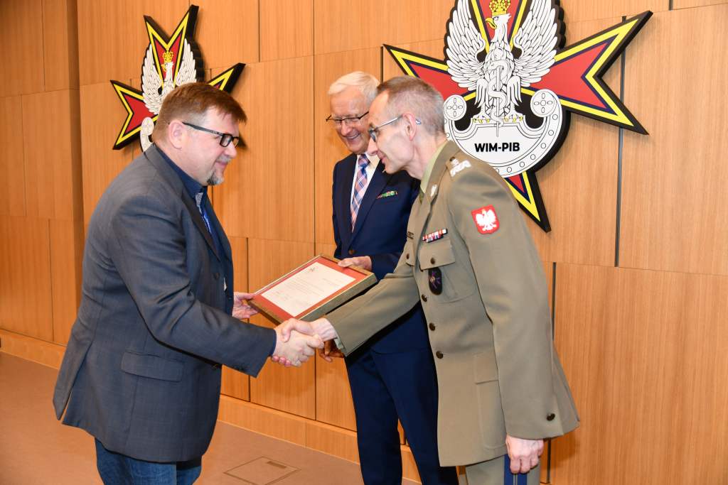 Wojciech Marczyński i Grzegorz Gielerak wręczają dyplom członkowi Rady.