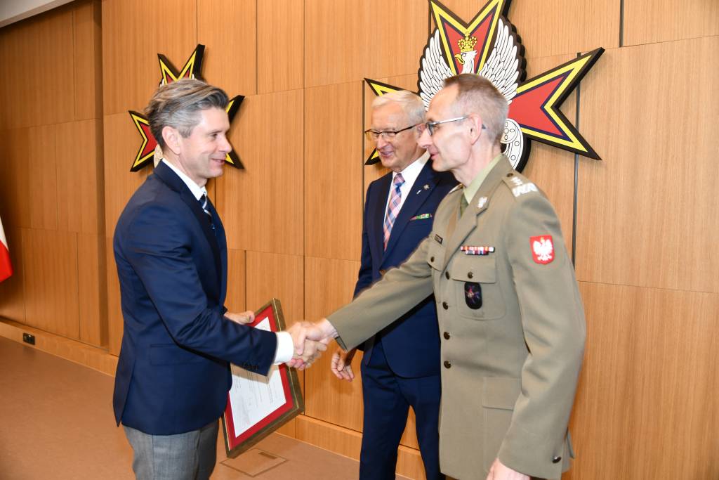 Wojciech Marczyński i Grzegorz Gielerak wręczają dyplom członkowi rady.