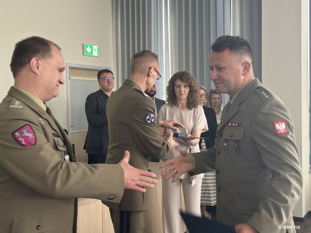 Student w mundurze wojskowym ściska rękę pracownikowi WIM-PIB ubranemu w wojskowy mundur.
