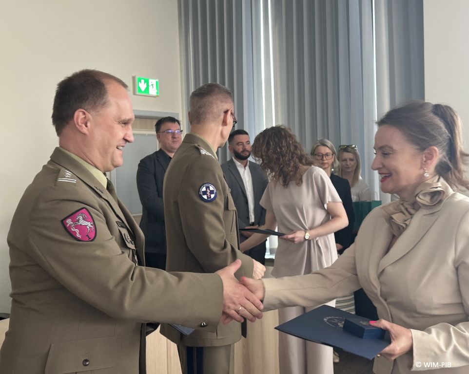 Studentka ściska rękę pracownikowi WIM-PIB ubranemu w wojskowy mundur.