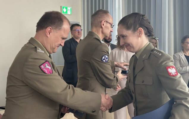 Pracownik WIM-PIB gratuluje studentce ubranej w wojskowy mundur.