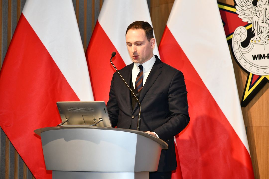Jan Gębalski przy mównicy z tyłu flagi RP.
