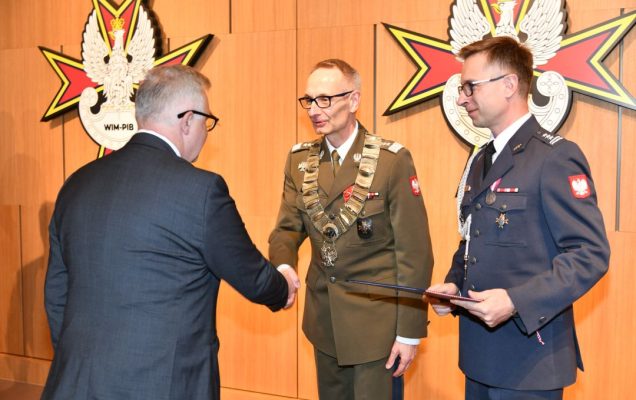 prof. Grzegorz Gielerak i prof. Paweł Krzesiński wręczają dyplom doktorski Hubertowi Burdziakowi.