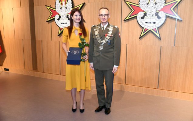 Dyrektor WIM z doktor Martą Kwiatkowską trzymającą nagrodę i czerwoną różę.