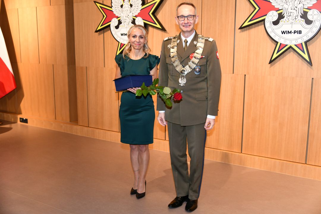Małgorzata Złotkowska Główny specjalista ds. komunikacji wewnętrznej WIM z dyplomem i czerwona różą w rękach obok dyrektora WIM.