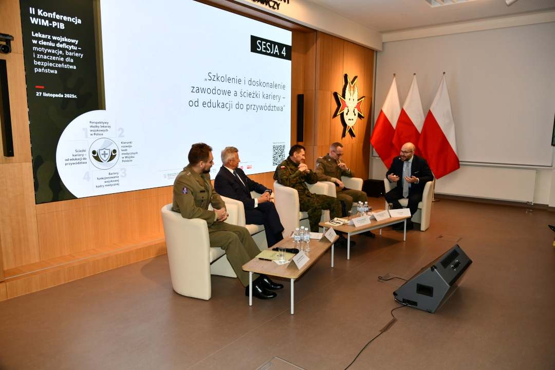 Uczestnicy siedzący w fotelach podczas panelu dyskusyjnego, za ich plecami wyświetlony fragment prezentacji.