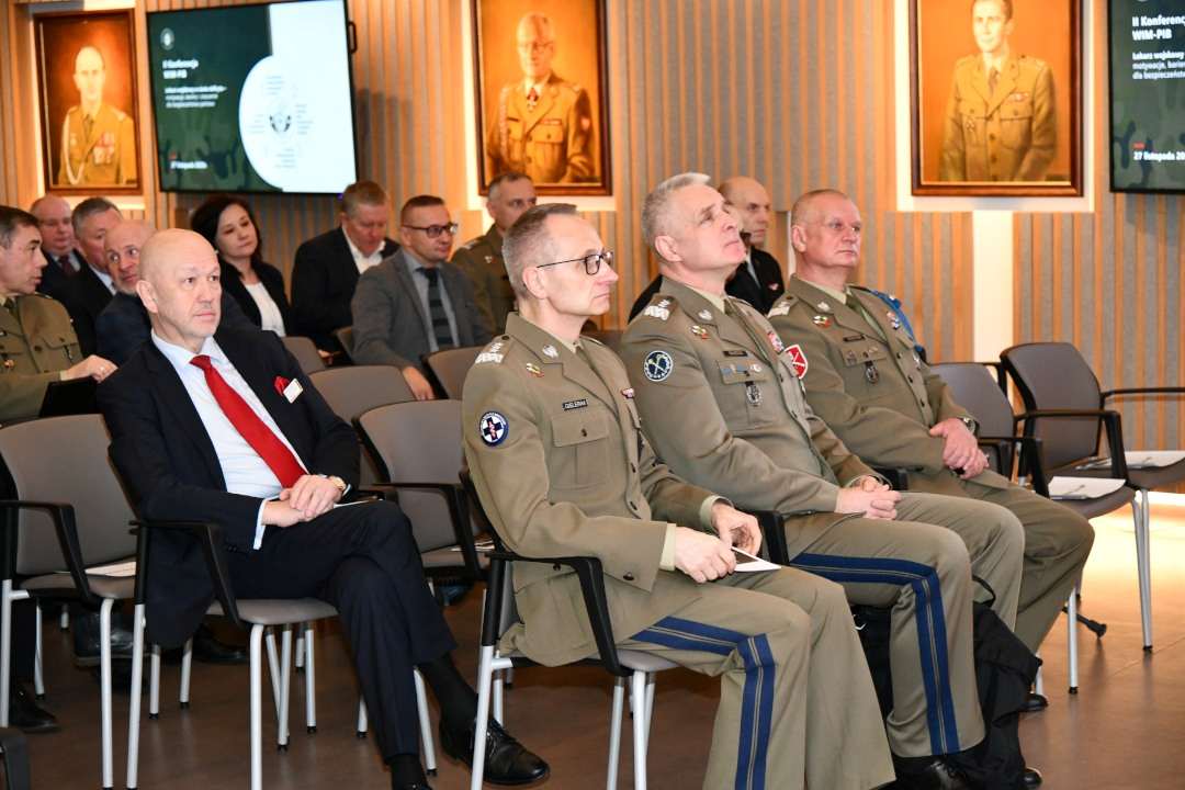 Słuchacze konferencji siedzący na auli Wojskowego Instytutu Medycznego. Na pierwszym planie Dyrektor WIM-PIB Grzegorz Gielerak.