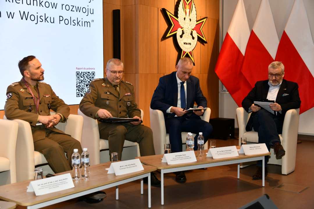 Uczestnicy siedzący w fotelach podczas panelu dyskusyjnego, za ich plecami wyświetlony fragment prezentacji.