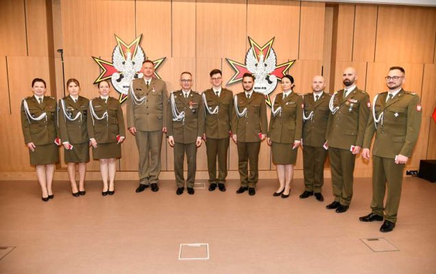 Dyrektor WIM z odznaczonymi pracownikami pozują do zdjęcia grupowego.