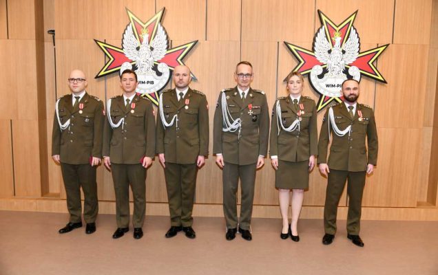 Dyrektor WIM pozuje do zdjęcia z odznaczonymi pracownikami. Wszyscy ubrani są w mundury wojskowe.