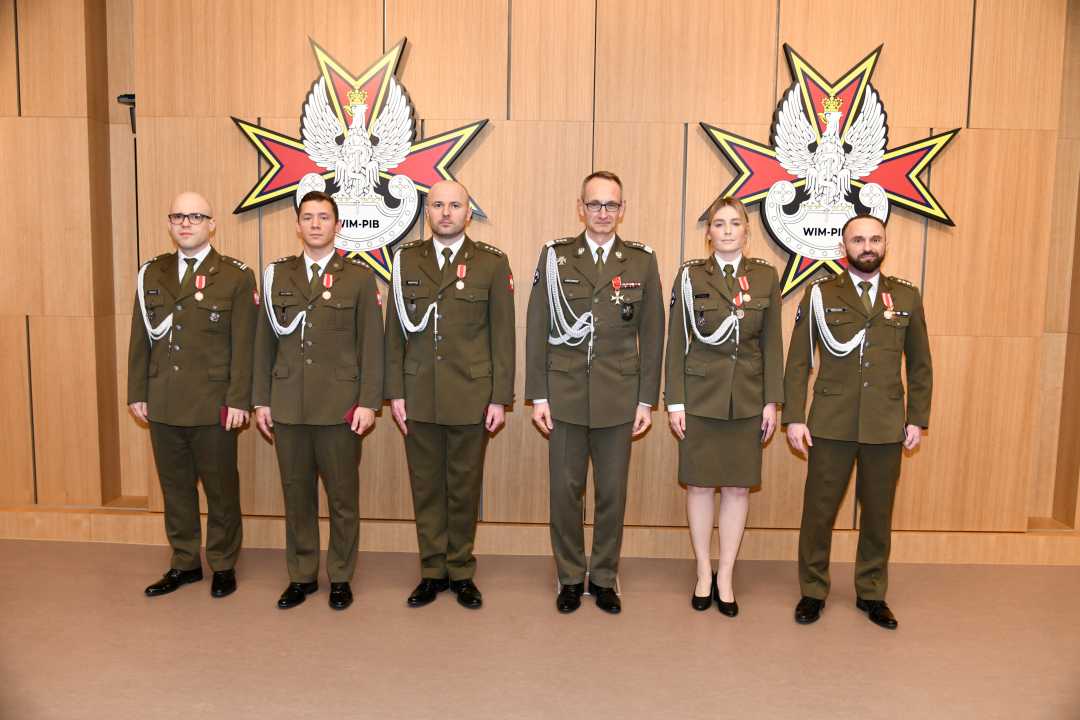 Dyrektor WIM pozuje do zdjęcia z odznaczonymi pracownikami. Wszyscy ubrani są w mundury wojskowe.