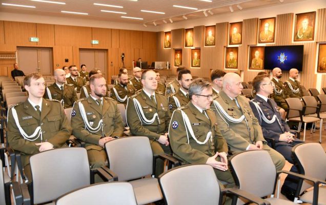 Pracownicy ubrani w wojskowe mundury siedzący na auli WIM podczas uroczystości.