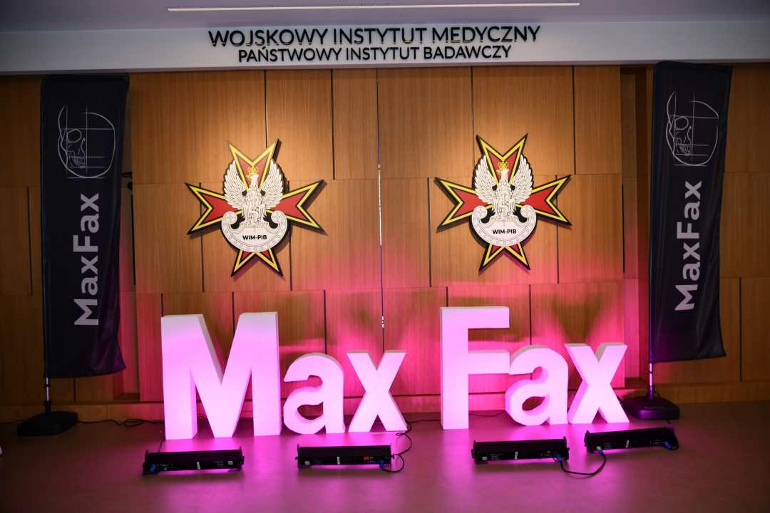 Podświetlony napis Max Fax na auli WIM. Za napisem na ścianę 2 logotypy WIM-PIB.