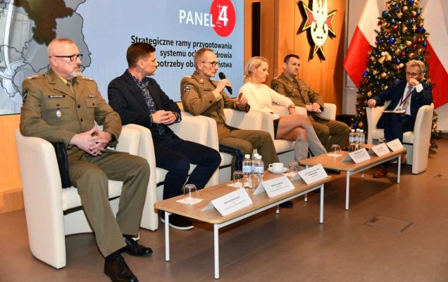 Dyrektor WIM Grzegorz Gielerak z panelistami podczas sesji, zabiera głos. Za nimi fragment wyświetlanej prezentacji.