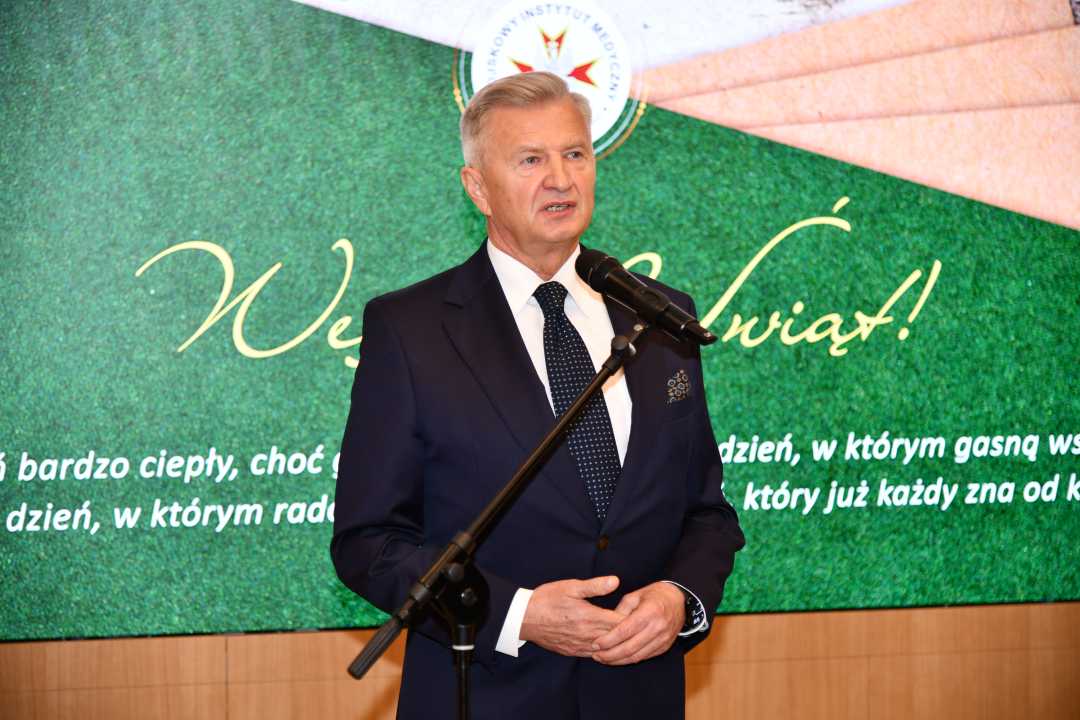 Podsekretarz Stanu w Ministerstwie Obrony Narodowej, Pan Stanisław Wziątek przemawia na auli WIM. Za jego plecami na ekranie wyświetlone życzenia bożonarodzeniowe.
