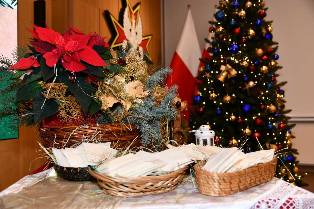 Trzy koszyczki z opłatkiem na stole wysypanym siankiem.