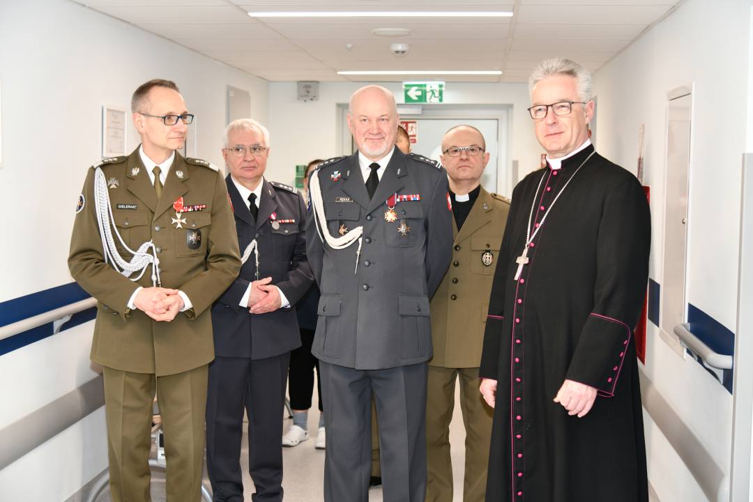 Biskup, dyrektor WIM, Marek Rękas, Jacek Doniec na korytarzu szpitalnym pozują do zdjęcie z biskupem.