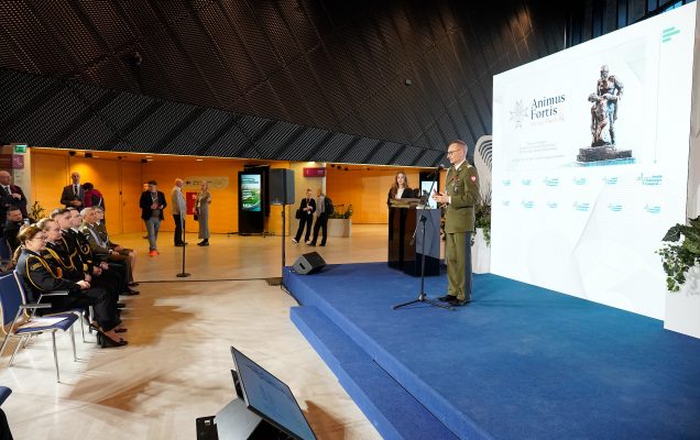 Dyrektor WIM Grzegorz Gielerak na scenie za nim wielki ekran z wyświetloną planszą Animus Fortis.