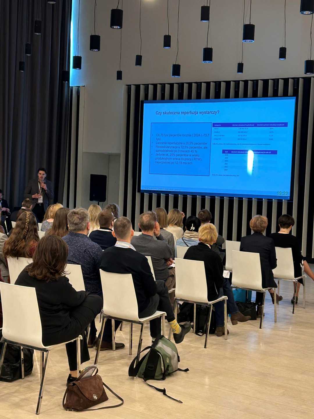 Ujęcie z tyłu sali słuchaczy podczas wykładu na sali konferencyjnej.