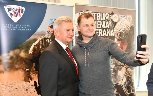 Uczestnik spotkania robi selfie z Stanisławem Wziątkiem na tle ścianki Centrum Leczenia Weterana.
