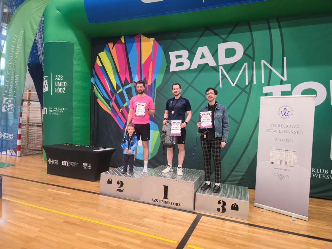 Wojciech Kurzyński na hali sportowej stoi na podium z 1 miejscem.