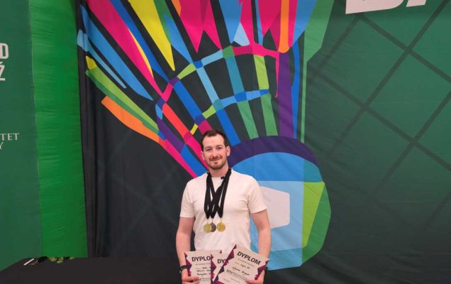 Wojciech Kurzyński na hali sportowej z medalami na szyi, prezentujący dyplomy.