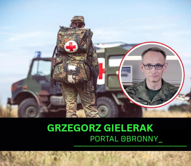 Żołnierz na poligonie idący do karetki wojskowej. W kółku Grzegorz Gielerak.