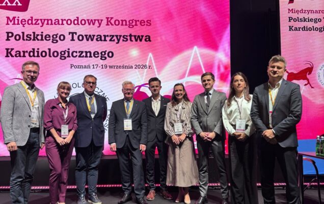 Uczestnicy Międzynarodowego Kongresu w grupie uśmiechnięci, za nimi główny szyld wydarzenia.