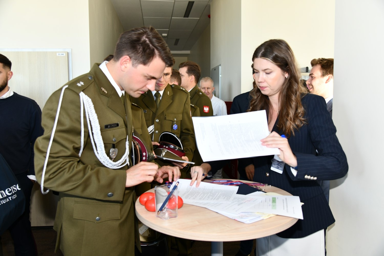 Stoisko z ankietami dla uczestników inauguracji. Młody lekarz uzupełnia ankietę.