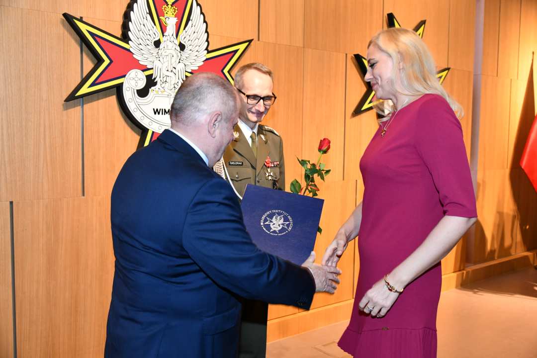 Alojzy Nowak i Grzegorz Gielerak wręczają pracowniczce WIM dyplom.