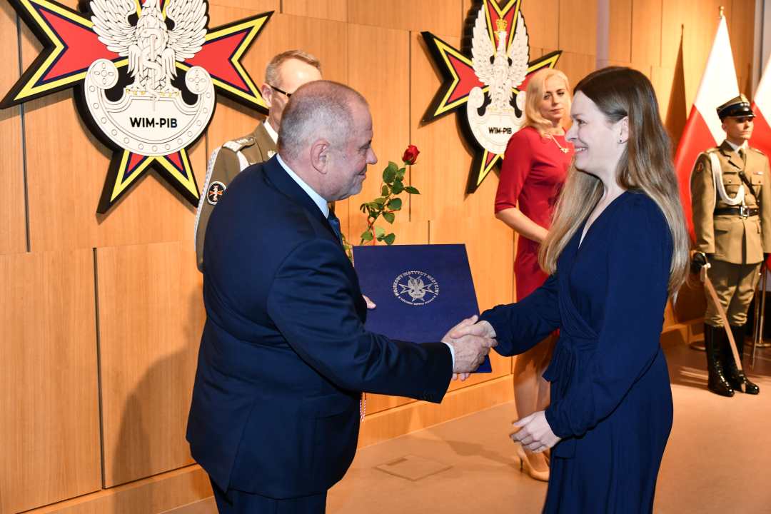 Alojzy Nowak i Grzegorz Gielerak wręczają pracowniczce WIM dyplom.