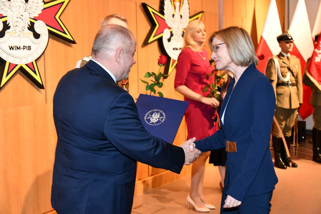Alojzy Nowak i Grzegorz Gielerak wręczają pracowniczce WIM dyplom.