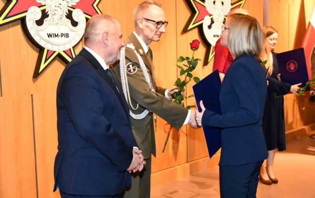 Alojzy Nowak i Grzegorz Gielerak wręczają pracowniczce WIM dyplom.