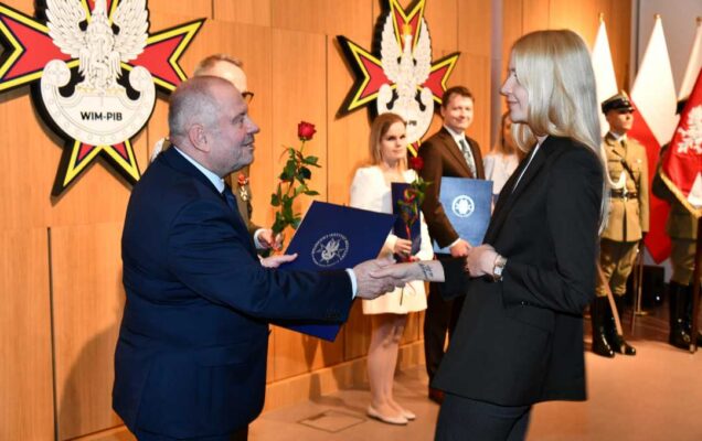 Alojzy Nowak i Grzegorz Gielerak wręczają pracowniczce WIM dyplom.