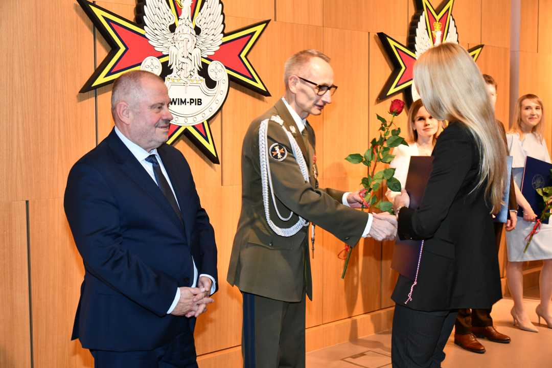 Alojzy Nowak i Grzegorz Gielerak wręczają pracowniczce WIM dyplom.